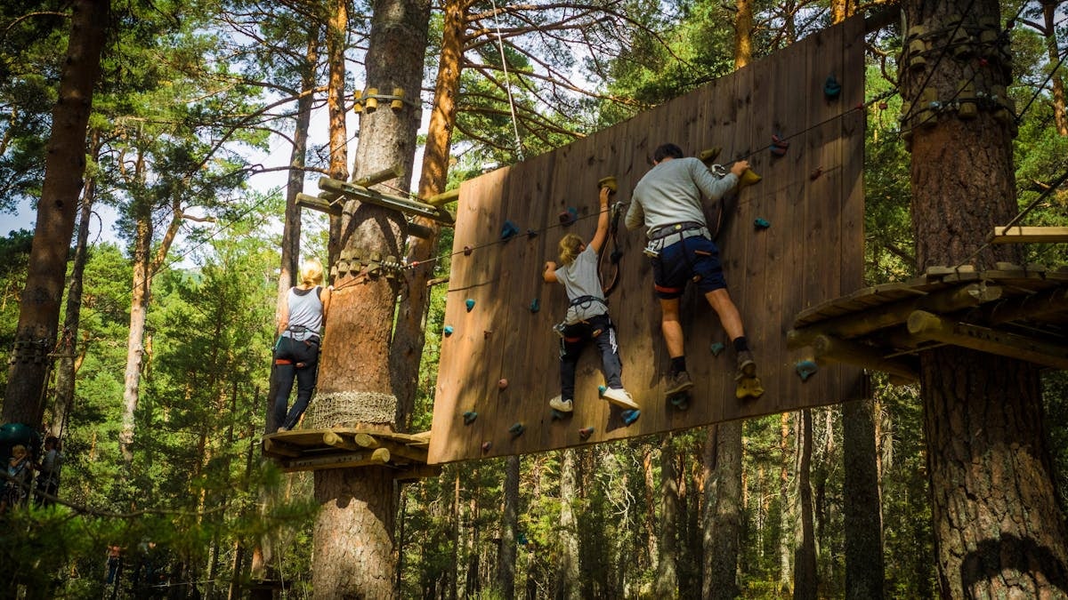 Family enjoying an outdoor climbing adventure in Cercedilla, Madrid amidst lush greenery.