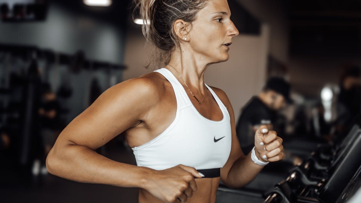 Fit woman exercising on a treadmill in a modern gym setting.